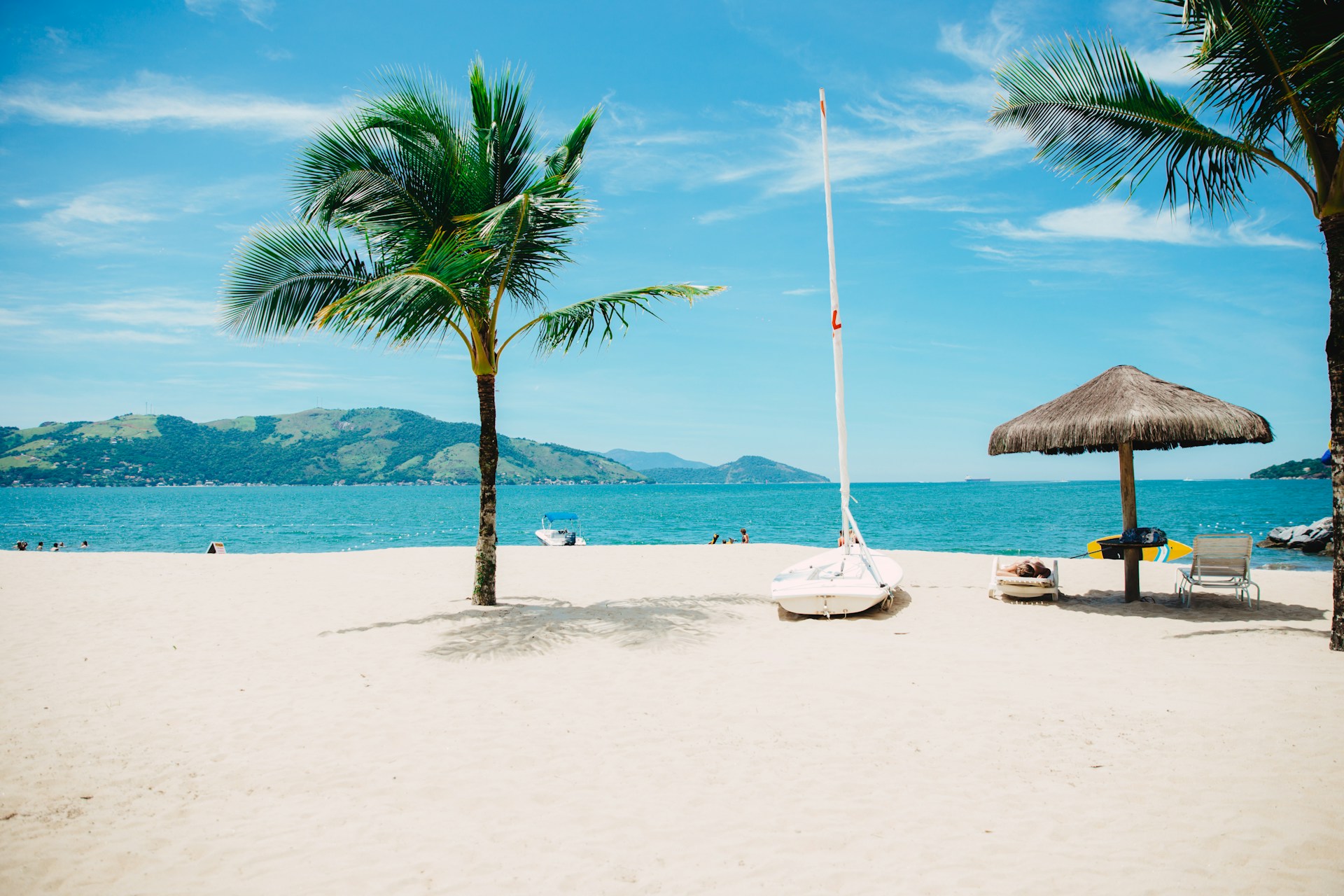 A clear beach with palm trees and huts